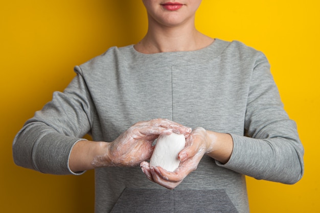 La donna tiene e mostra il sapone tra le mani. Palmi e dita in schiuma insaponata allungano il sapone in avanti. Disinfezione delle mani nella lotta contro il coronavirus.