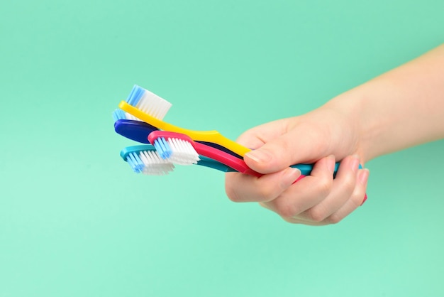 La donna tiene gli spazzolini da denti in mano su uno sfondo verde