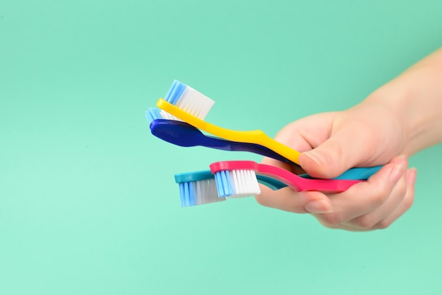 La donna tiene gli spazzolini da denti in mano su uno sfondo verde.