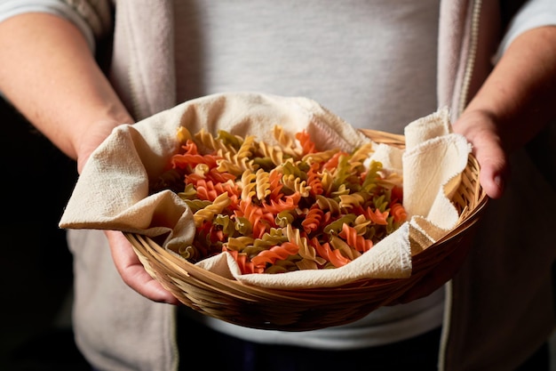 La donna tiene i fusilli tricolori in un cestino