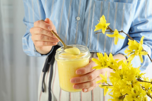 La donna tiene il cucchiaio e il barattolo di cagliata di limone