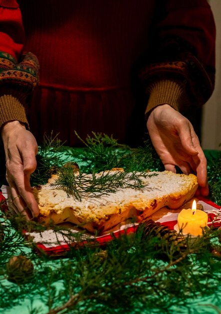 La donna tiene il cupcake di Natale sotto forma di albero di Natale nelle sue mani sul tavolo festivo