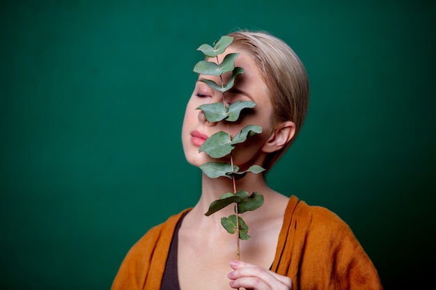 La donna tiene il ramo di eucalipto sulla scena verde