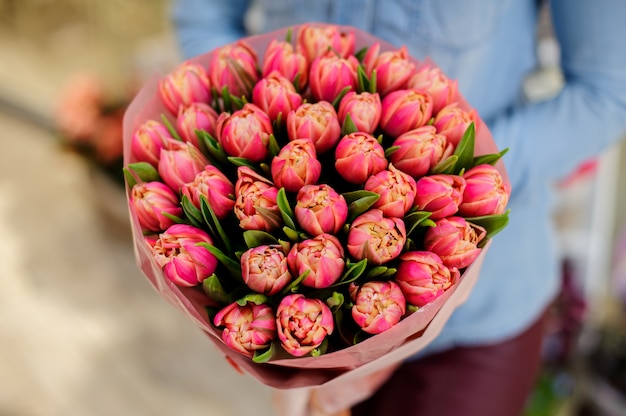 La donna tiene in mano un bellissimo mazzo di tulipani rosa