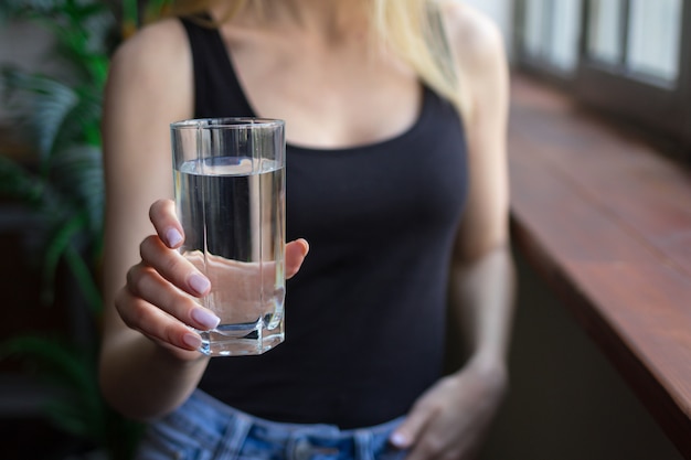 la donna tiene in mano un bicchiere d'acqua, benefici idrici per la salute