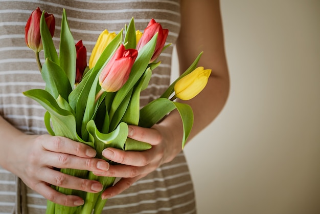 La donna tiene in mano un mazzo di fiori di tulipano freschi, da vicino