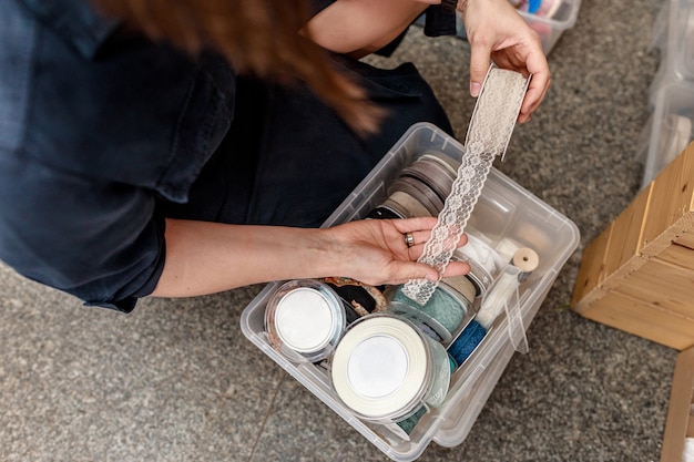 La donna tiene in mano un nastro di pizzo bianco per la decorazione e l'artigianato. Regalo fai-da-te e concetto di decorazione. Fai da te