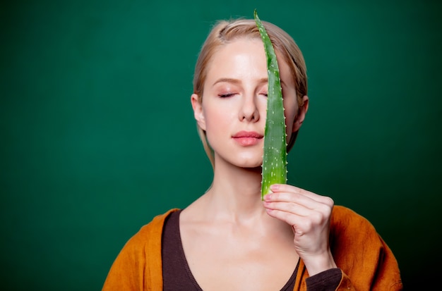 La donna tiene l'aloe in mano vicino a un viso sulla scena verde