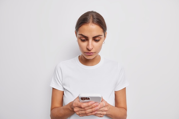 la donna tiene l'applicazione per il download del telefono cellulare invia messaggi di testo a un amico vestito con una maglietta casual su bianco