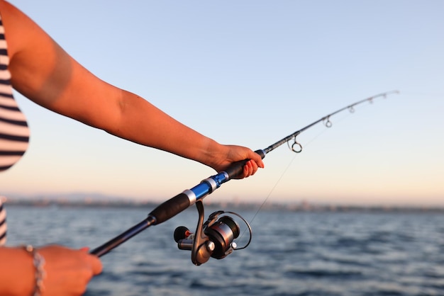 La donna tiene la canna da spinning nelle sue mani e pesca in vista mare dalla pescatrice al mare e