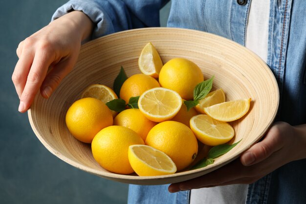 La donna tiene la ciotola con i limoni. Frutto maturo