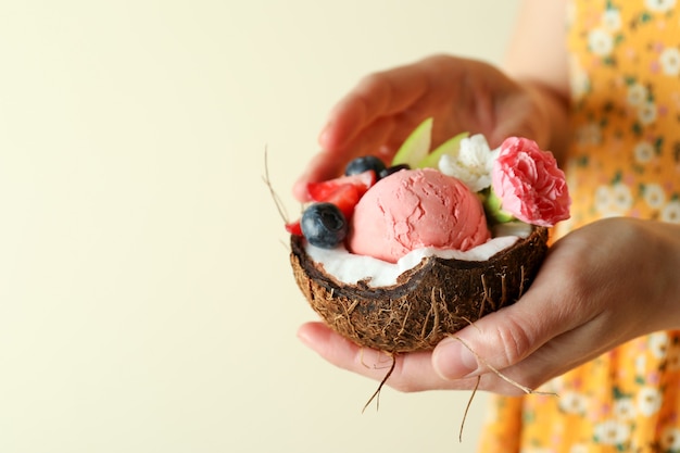 La donna tiene la noce di cocco con gelato alla frutta, primi piani