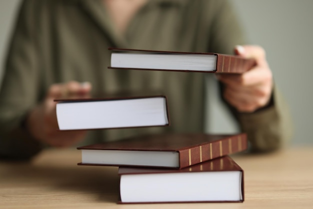 La donna tiene libri di testo spessi di letteratura seduti al tavolo di legno pila di libri con marrone