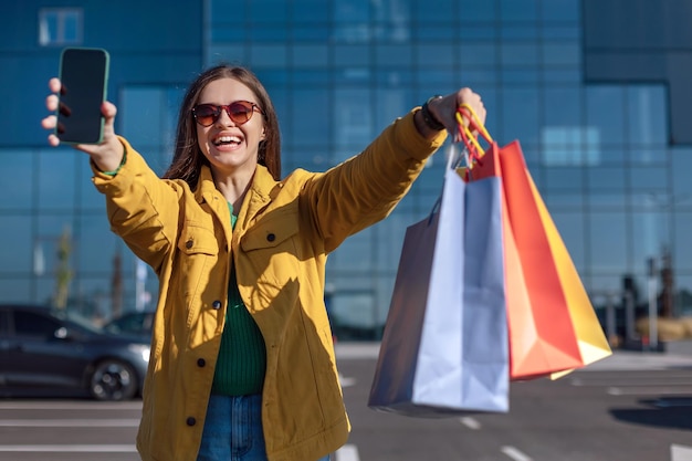 La donna tiene lo smartphone e la borsa della spesa con una spesa in mano