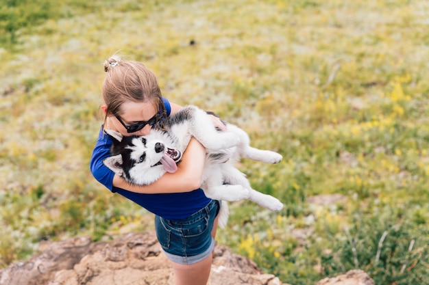 la donna tiene un cane tra le braccia. Husky nella natura.