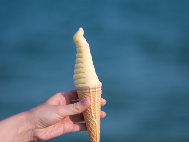 La donna tiene un gustoso gelato sulla spiaggia.