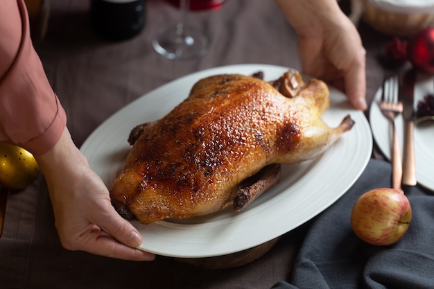 La donna tiene un piatto bianco con anatra arrosto croccante, pronta per essere servita