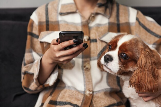 La donna tiene un telefono cellulare in mano e il cane guarda il telefono