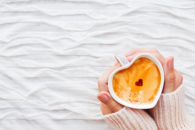 La donna tiene una tazza di caffè caldo con cuore di cannella