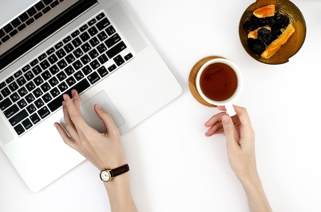 La donna tocca il computer portatile e tiene tazza di tè su sfondo bianco