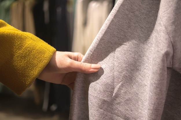 La donna tocca il materiale del tessuto dei vestiti e sceglie un nuovo negozio di abbigliamento e lo shopping backgrou ...