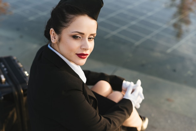 La donna triste dell'hostess in uniforme si siede sui gradini