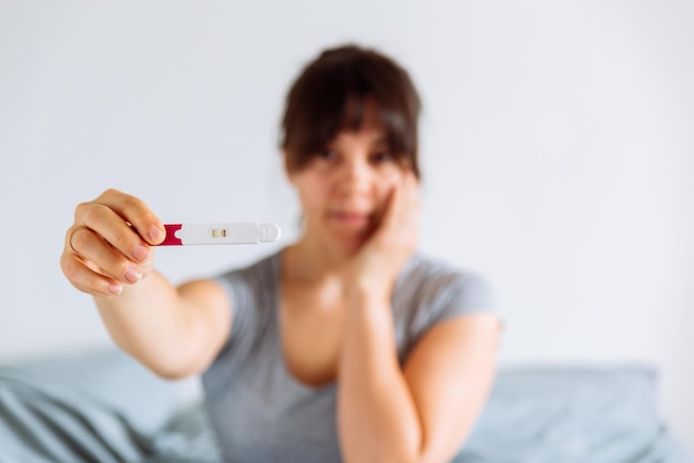 La donna triste mostra test di gravidanza negativo