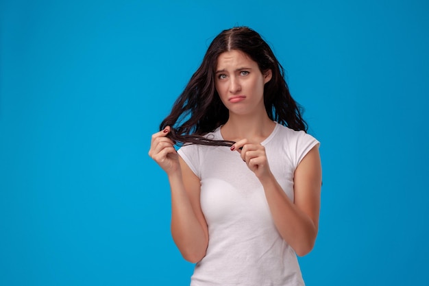 La donna triste sta tirando i suoi capelli su fondo blu