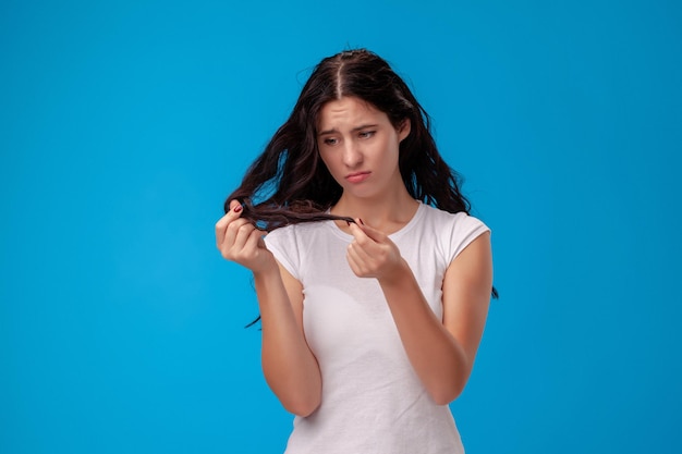 La donna triste sta tirando i suoi capelli su fondo blu