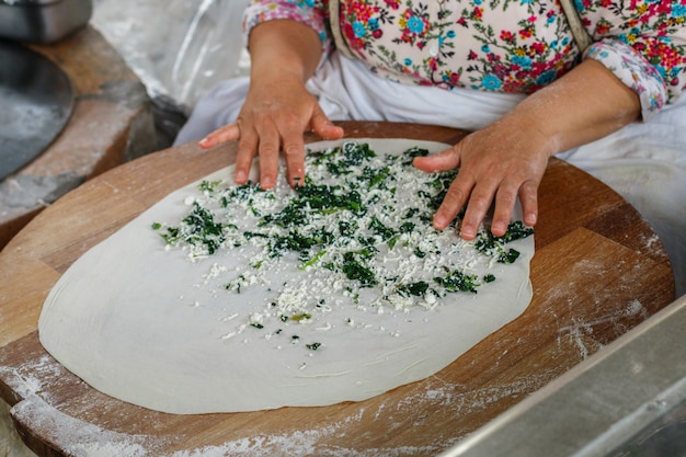 La donna turca prepara Gozleme - piatto tradizionale a forma di focaccia farcita con verdure e formaggio