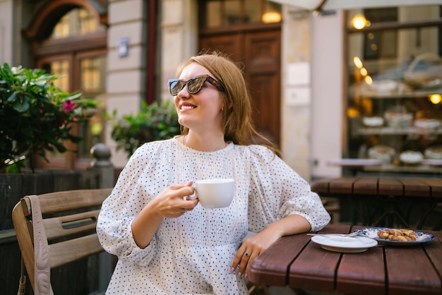 La donna turistica gode dell'architettura delle strade della città con una tazza di caffè Concetto di viaggio e vacanza