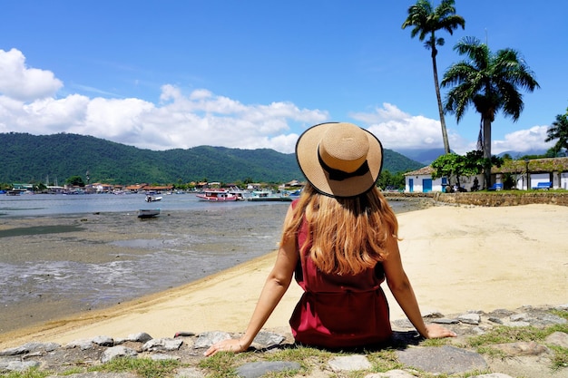 La donna turistica si rilassa seduta pacifica sulla parete nella destinazione tropicale