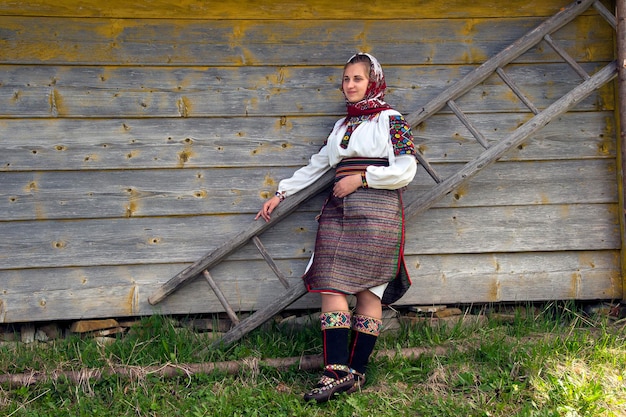 La donna ucraina in un autentico costume Hutsul si trova vicino a una scala