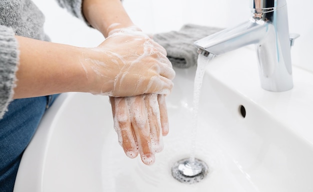 La donna usa il sapone e si lava le mani sotto il rubinetto dell'acqua. Dettaglio della mano di concetto di igiene.