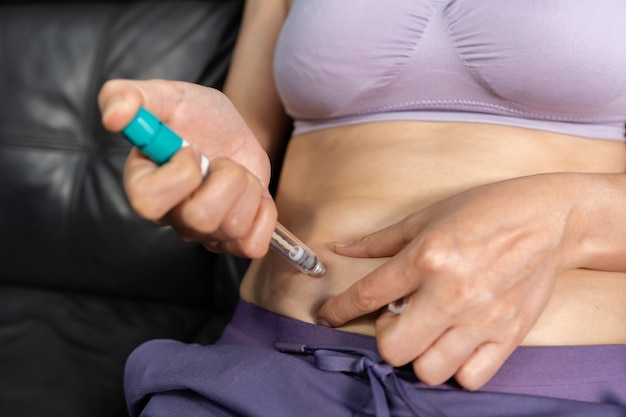 La donna usa una siringa con penna preriempita per portare l'FSH (ormone follicolo stimolante) nell'addome per stimolare le ovaie