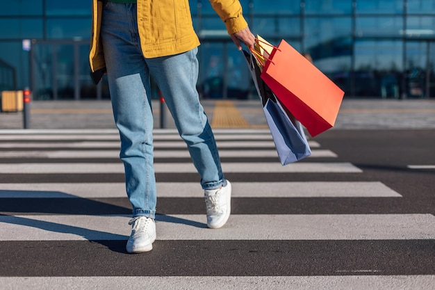 La donna va attraversamento pedonale da un centro commerciale con carrello con generi alimentari