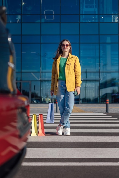 La donna va attraversamento pedonale da un centro commerciale con carrello con generi alimentari