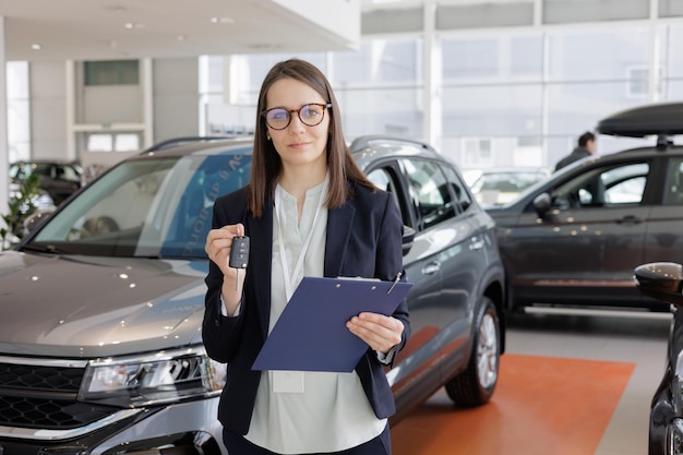 La donna vende un'auto presso un concessionario di automobili e consegna le chiavi all'acquirente