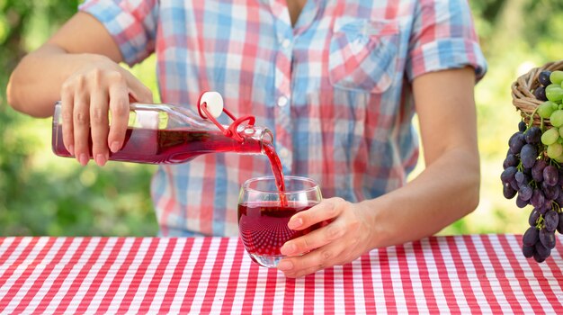 La donna versa il succo d'uva o il vino in un bicchiere