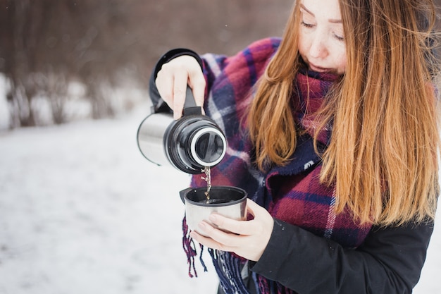 La donna versa il tè caldo o beve da thermos, passeggiata invernale, escursionismo, inverno, vestiti invernali