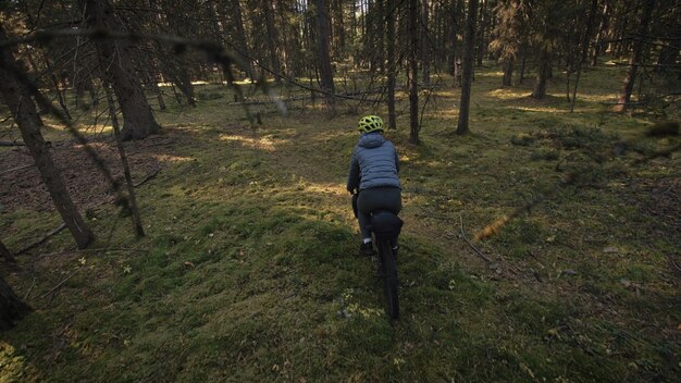 La donna viaggia su terreni misti cicloturismo con bici bikepacking outdoor Il viaggiatore viaggio con borse da bici Elegante bikepacking abbigliamento sportivo da bici nei colori verde nero Magico parco forestale