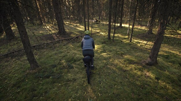 La donna viaggia su terreni misti cicloturismo con bici bikepacking outdoor Il viaggiatore viaggio con borse da bici Elegante bikepacking abbigliamento sportivo da bici nei colori verde nero Magico parco forestale