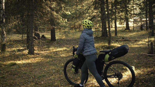 La donna viaggia su terreno misto cicloturismo con bike bikepacking. Il viaggio del viaggiatore con le borse della bicicletta. Parco della foresta magica.