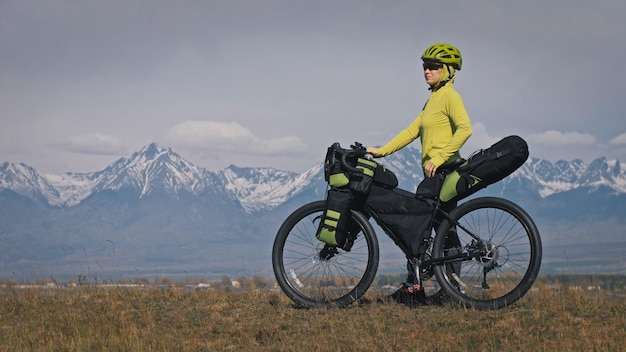 La donna viaggia su terreno misto cicloturismo con bikepacking. Il viaggio del viaggiatore con le borse della bicicletta. Bikepacking da turismo sportivo.