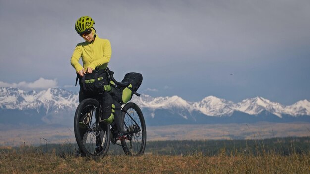 La donna viaggia su terreno misto cicloturismo con bikepacking. Il viaggio del viaggiatore con le borse della bicicletta. Bikepacking da turismo sportivo.