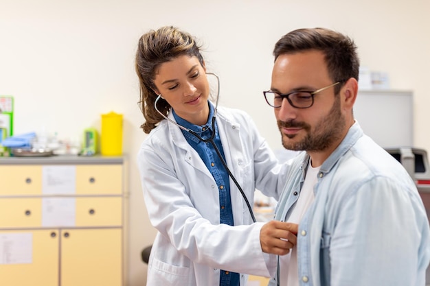 La dottoressa caucasica premurosa usa il fonendoscopio esamina la frequenza cardiaca del paziente maschio durante la consultazione in ospedale L'infermiera o il medico di famiglia usano lo stetoscopio ascoltano il battito cardiaco dell'uomo in clinica