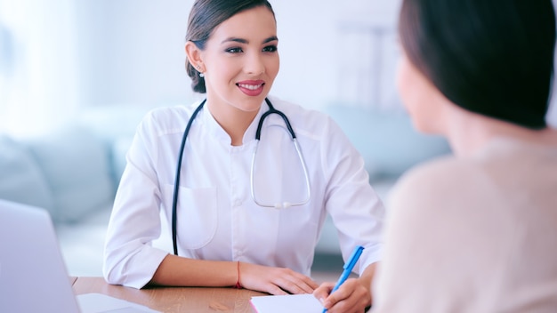 La dottoressa comunica con il paziente in ufficio e prescrive farmaci