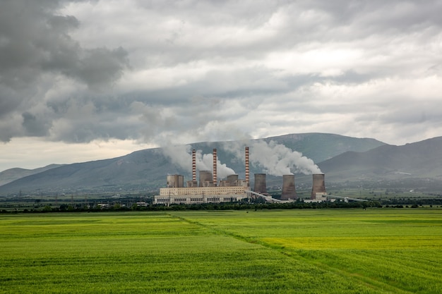 La fabbrica fa le nuvole nel campo verde