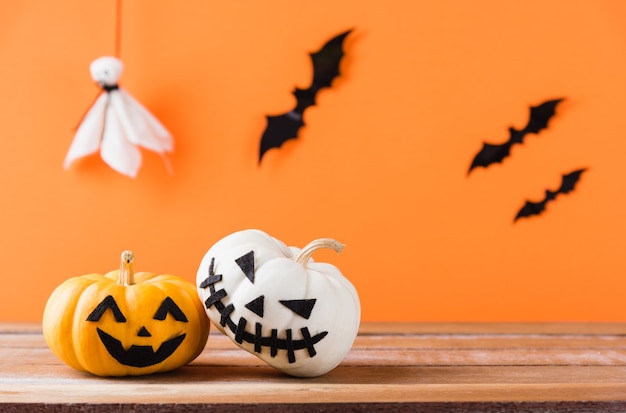 La faccia spettrale di zucca fantasma di jack o lanterna, ragno nero e pipistrelli sul tavolo di legno