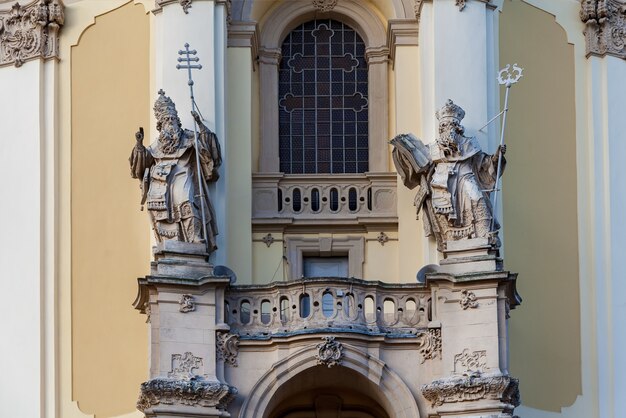 La facciata della vecchia chiesa con sculture in pietra dei santi davanti a un portone d'ingresso A